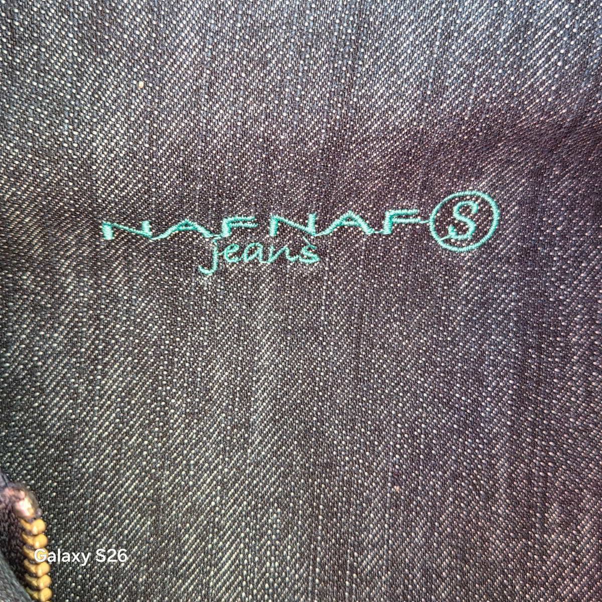 Détail du logo Naf Naf brodé à l'intérieur de la veste en jean femme style bomber.