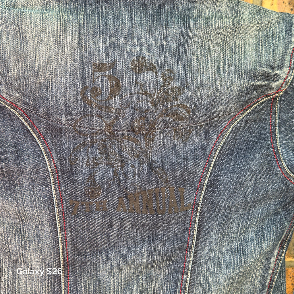 Gros plan sur la broderie décorative au dos de la veste en jean Naf Naf Jeans bleu délavé.