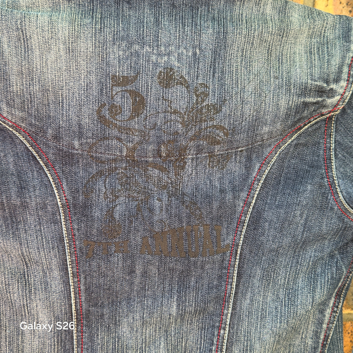 Gros plan sur la broderie décorative au dos de la veste en jean Naf Naf Jeans bleu délavé.