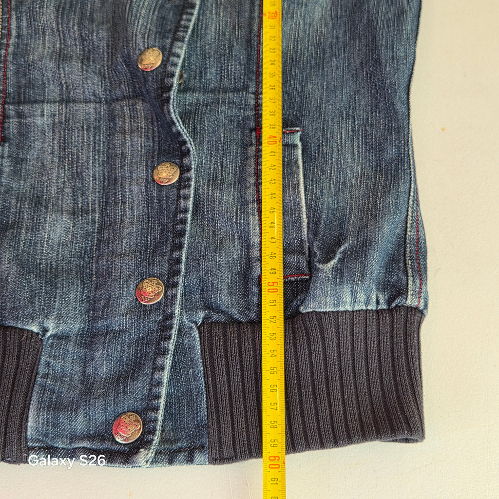 Mesure de la longueur de la veste en jean bomber Naf Naf femme avec un mètre ruban jaune.